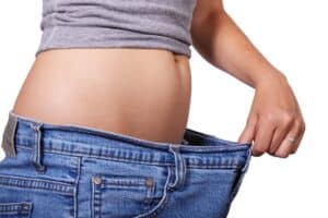 Frau mit viel zu großer Hose nach dem abnehmen ohne Diät
