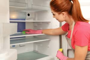 Ein Frau beim auswischen des Kühlschrank
