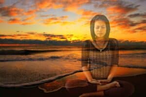 Asiatische Frau sitzt am Strand und meditiert